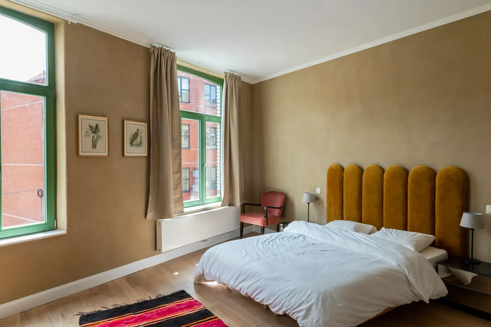 ICI© — chambre à enduit ocre, châssis vert et tête de lit velours moutarde